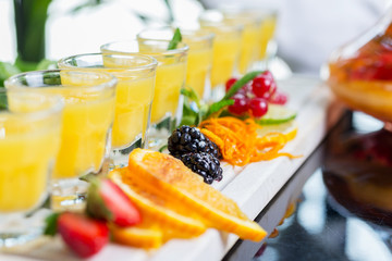 Set of several bright glasses with cold alcoholic cocktail with orange juice on a wooden table in a restaurant with ice and creative decoration of berries, fresh mint and orange slices. soft focus