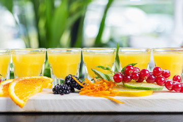 Set of several bright glasses with cold alcoholic cocktail with orange juice on a wooden table in a restaurant with ice and creative decoration of berries, fresh mint and orange slices. soft focus