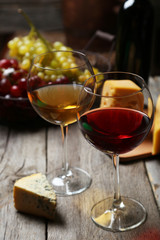Glass of red and white wine, cheeses and grapes 