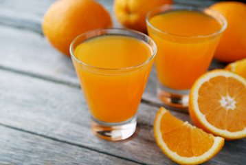 Glass of fresh orange juice on wooden background