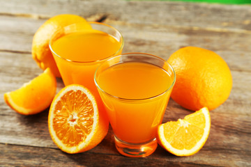 Glass of fresh orange juice on wooden background