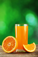 Glass of fresh orange juice on wooden background