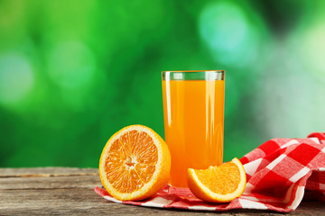 Glass of fresh orange juice on wooden background