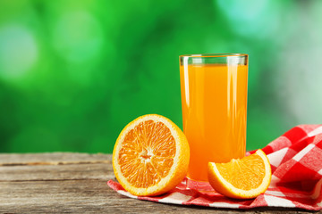 Glass of fresh orange juice on wooden background