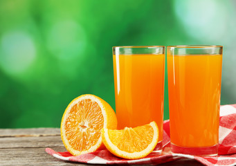 Glass of fresh orange juice on wooden background