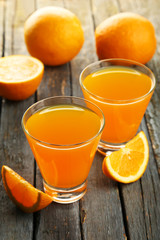 Glass of fresh orange juice on wooden background