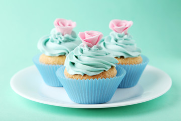 Tasty cupcake on plate on green background