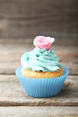 Tasty cupcake on grey wooden background