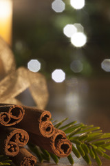 Cinnamon and a lit candle on a wooden table infront of a christm