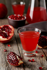 Pomegranate juice in glass on wooden background