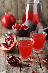 Pomegranate juice in glass on wooden background