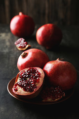 Delicious pomegranate fruit on plate on black background