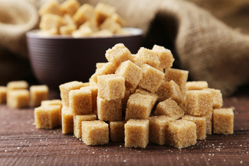 Brown sugar in spoon and bowl on wooden background