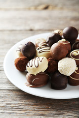 Chocolates on plate on grey wooden background
