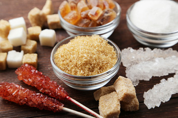 Brown sugar in spoon and bowl on wooden background