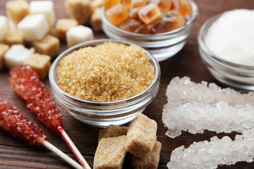 Brown sugar in spoon and bowl on wooden background