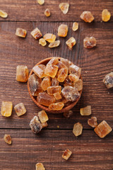 Brown sugar in spoon and bowl on wooden background