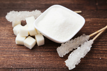 Brown sugar in spoon and bowl on wooden background
