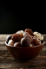 Chocolates in bowl on brown wooden background