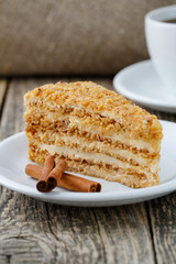 Tasty honey cake with cup of coffee on wooden background.