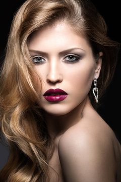 Beautiful woman with evening make-up, red lips and curls. Beauty face. Picture taken in the studio on a gray background.