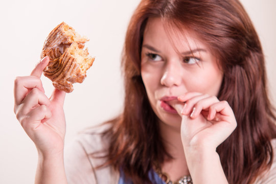 Woman eating a donut and licks her fingers