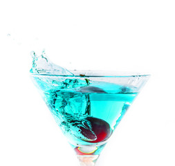 une cerise tombant dans un verre de cocktail