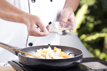 Chef putting the seasoning to the pan for cooking