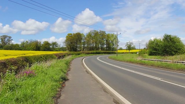 Busy road in Scotland with rapeseed fields on the sides