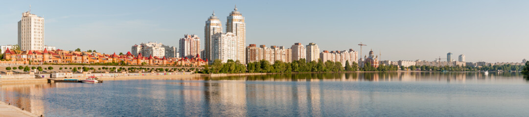 The first sun rays caresse the buildings close to the Dnieper river in Kiev, panoramic view