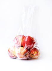 Red apples in clear plastic bag on white background