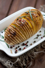 Close-up of hasselback potato with rosemary, sea salt and pepper