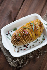Hasselback potato with herbs and spices, above view, studio shot
