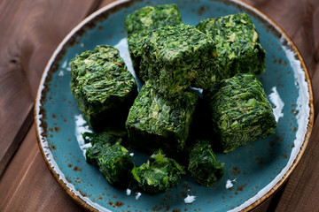 Turquoise plate with cubes of chopped and compressed spinach