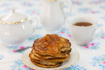 pear pancakes with jam and tea on a white plate and blue tablecloths