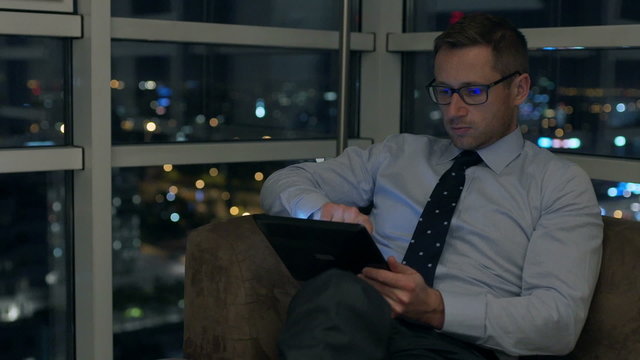 Businessman working on tablet in the apartment at night
