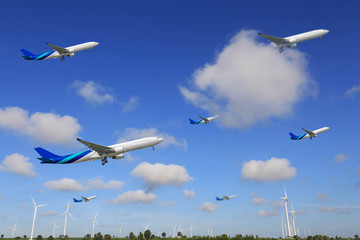 Airplane flying over turbine power generator with blue sky