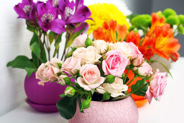Beautiful flowers in pots on light background