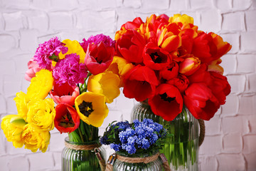 Beautiful flowers in vases on wall background
