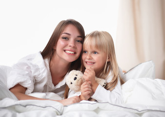 Woman and young girl lying in bed smiling