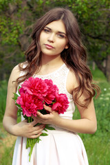 young beautiful girl holding peonies. warm day.