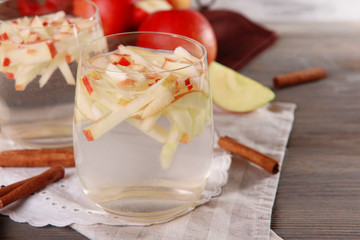 Glasses of apple cider with fruits and cinnamon on table close up