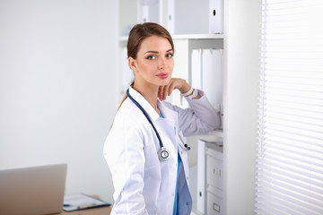 Woman doctor is standing near window 