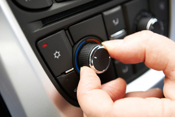 Close Up Of Hand Adjusting Car Air Conditioning Control On Dashb