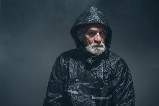 Humorless Old Man In Rain Jacket Looking At Camera