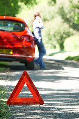 Female Driver Broken Down On Country Road With Warning Sign In F