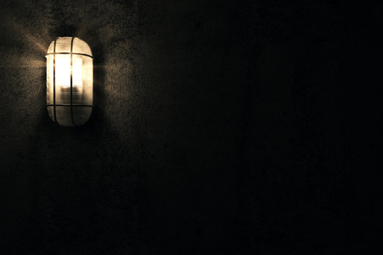 Illuminated Lamp on a Grunge Concrete Wall at Night