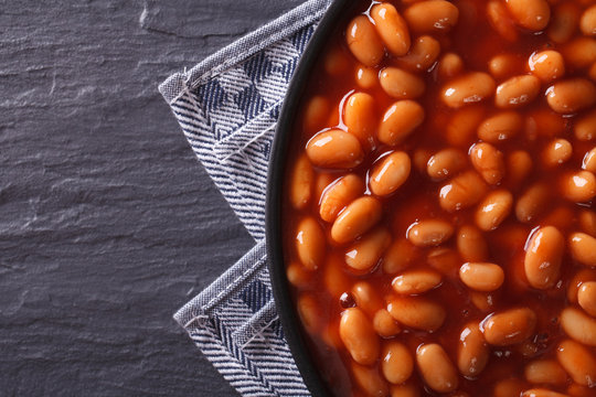 beans in tomato on a plate close-up. horizontal top view 
