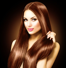Beautiful brunette woman touching her long shiny straight hair