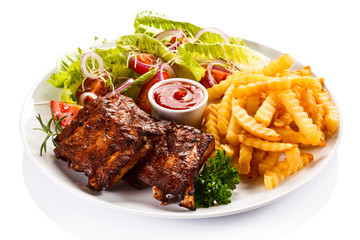 Grilled ribs, French fries and vegetables on white background 